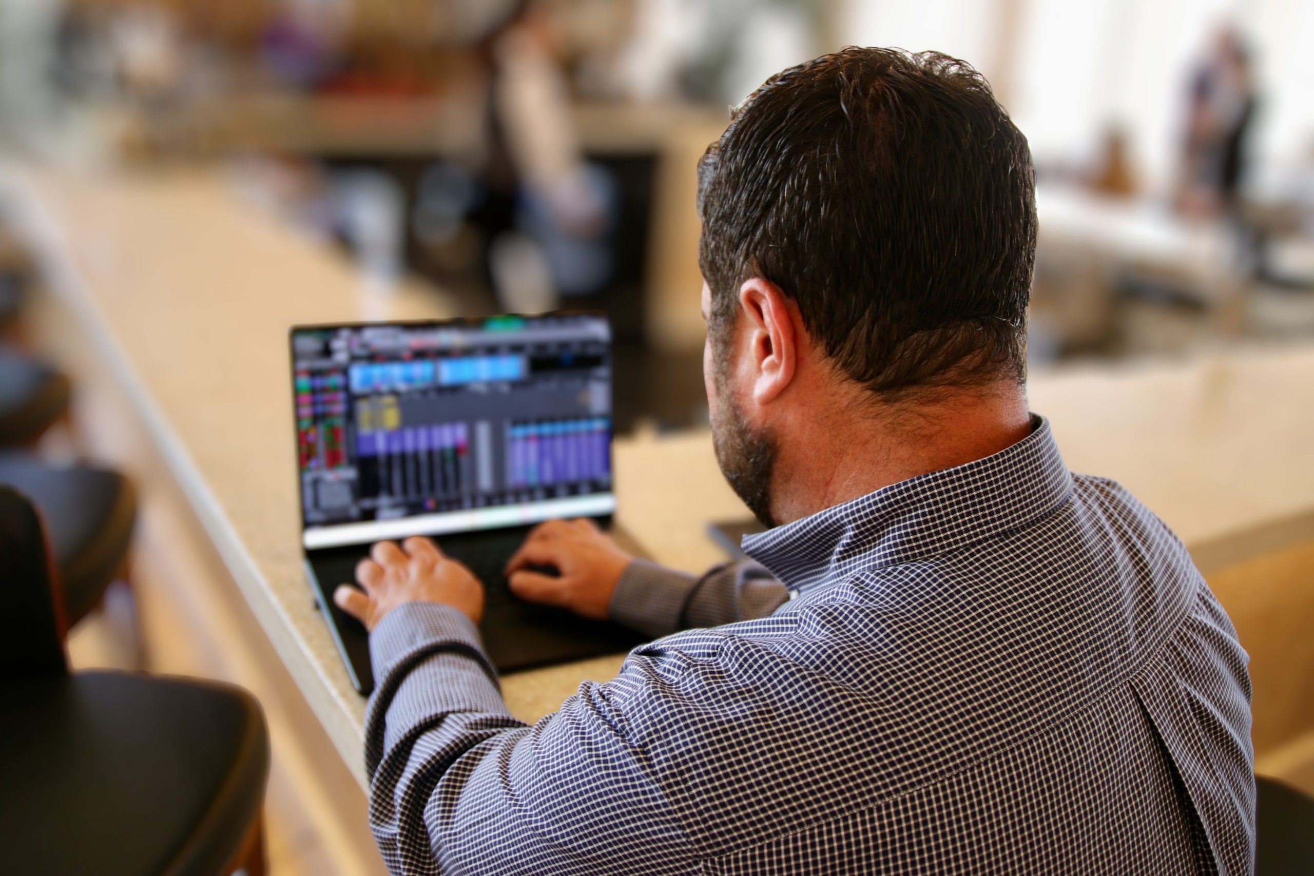 Join the Inner Circle Over the shoulder view of a man analyzing financial charts and stock market data on a laptop screen.